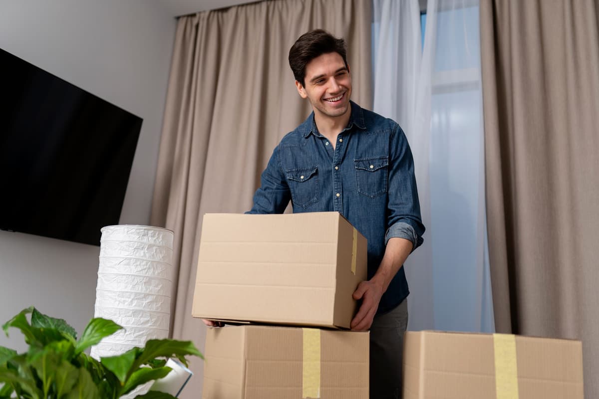 Smiling man carrying a moving box